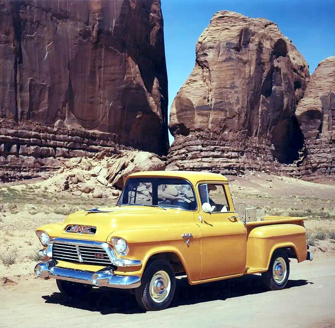Yellow 1957 GMC pickup truck in desert with red rock cliffs