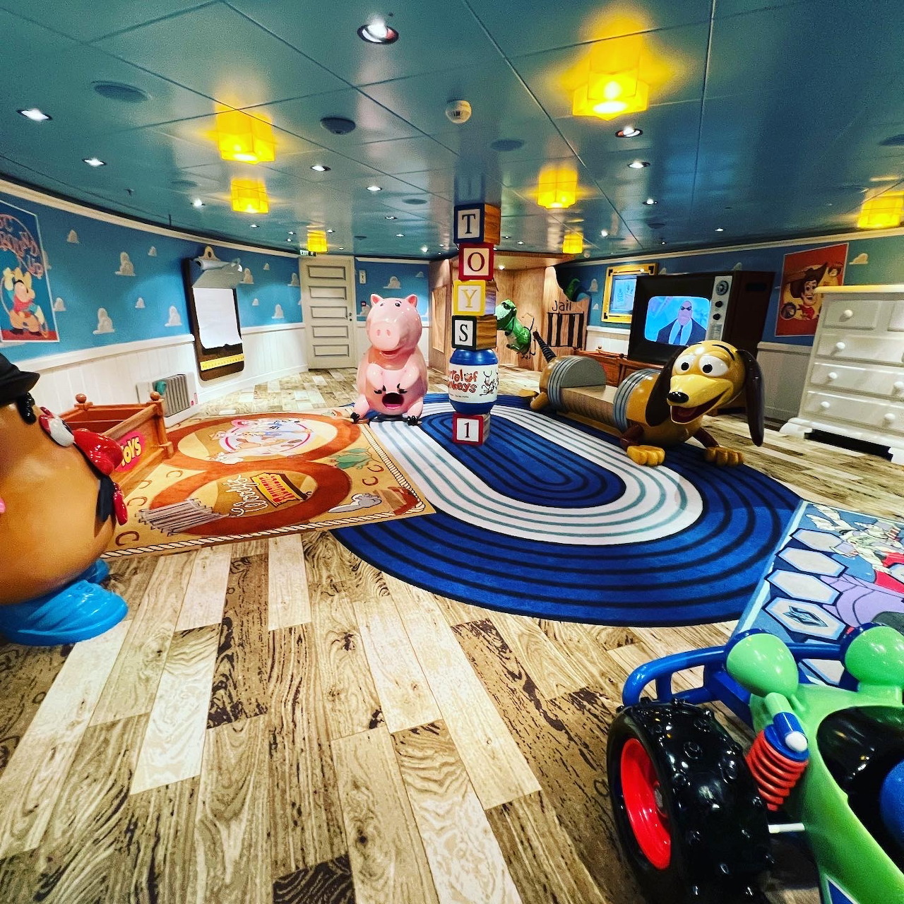 Colorful toy-filled child's bedroom with striped rug, cloud walls, and yellow hanging lamps