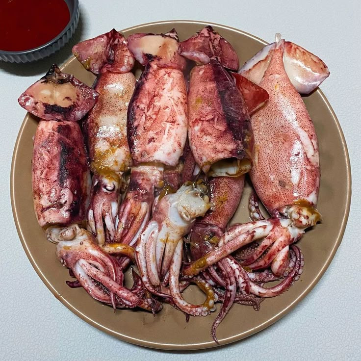 Overhead view of several cooked squid with tentacles on a beige plate