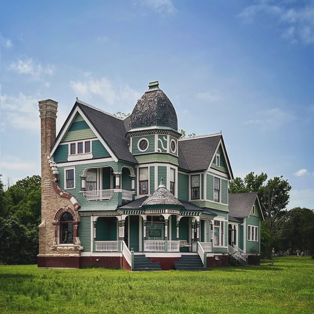 Green and white Victorian house with turret and front porch on lawn