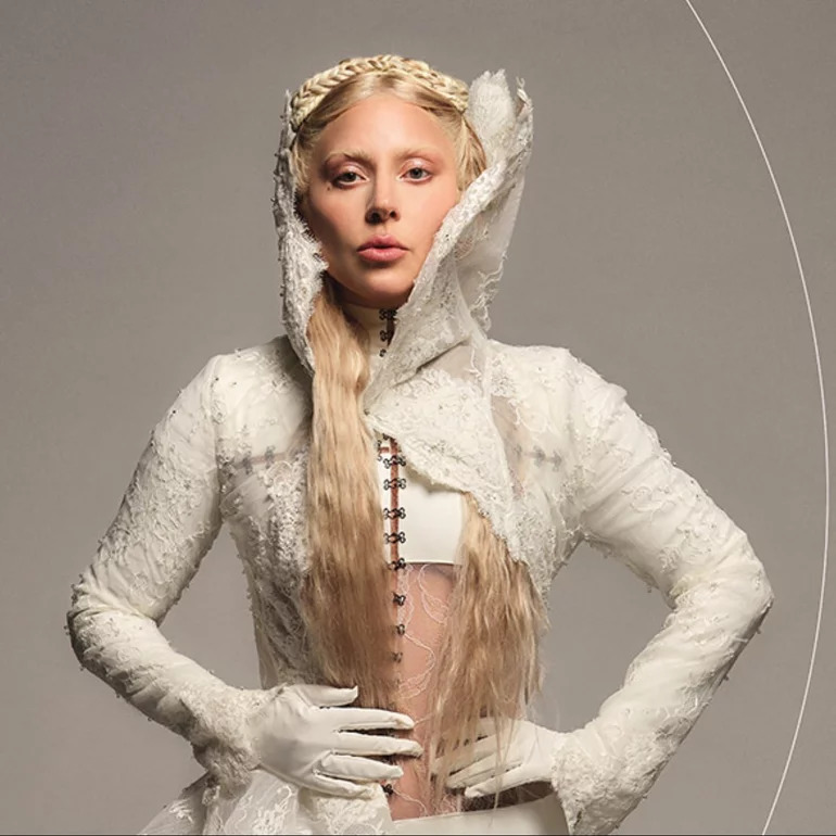 Lady Gaga in a white lace hooded outfit and gloves in a studio portrait