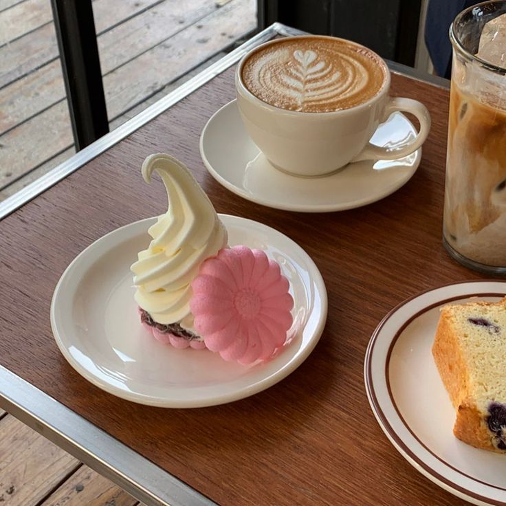 Cappuccino with latte art, pink dessert, cake slice, and iced coffee on wooden table