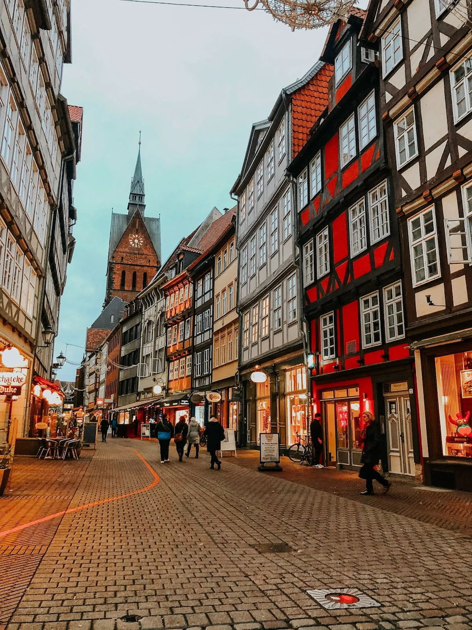 Cobblestone pedestrian street in Hannover old town with half-timbered buildings and a church spire