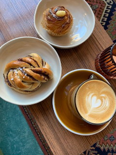 Top view of a latte with leaf foam art and two pastries on a wooden table