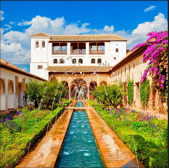 Generalife courtyard with a long fountain pool, green gardens, white arcades, and pink flowers.