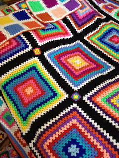 Colorful crocheted granny square blanket with concentric square patterns in many bright colors