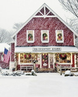 Snow-covered red country store with Christmas wreaths, garlands, and an American flag on the front porch