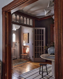 Victorian entryway with ornate wood arch, French door, hardwood floors and fireplace in background