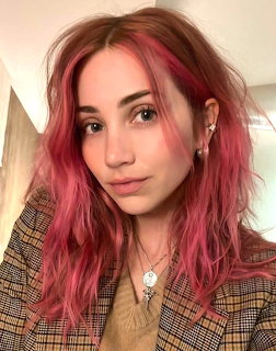 Emily Rudd portrait with pink hair, plaid blazer, and layered necklaces indoors