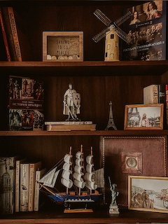 Dark wooden bookshelf with model windmill, Eiffel Tower, sailing ship, Statue of Liberty figurine, books and framed photos