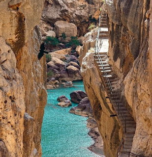 Wooden stairways in a narrow rocky gorge above clear turquoise water