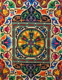 Colorful tentmakers quilt with intricate geometric and floral appliqué patterns and central mandala design