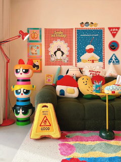 Colorful kids room with a green sofa, posters, toys, pillows, and a bright rug