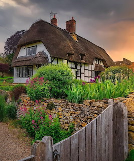 Thatched roof cottage with garden at sunset