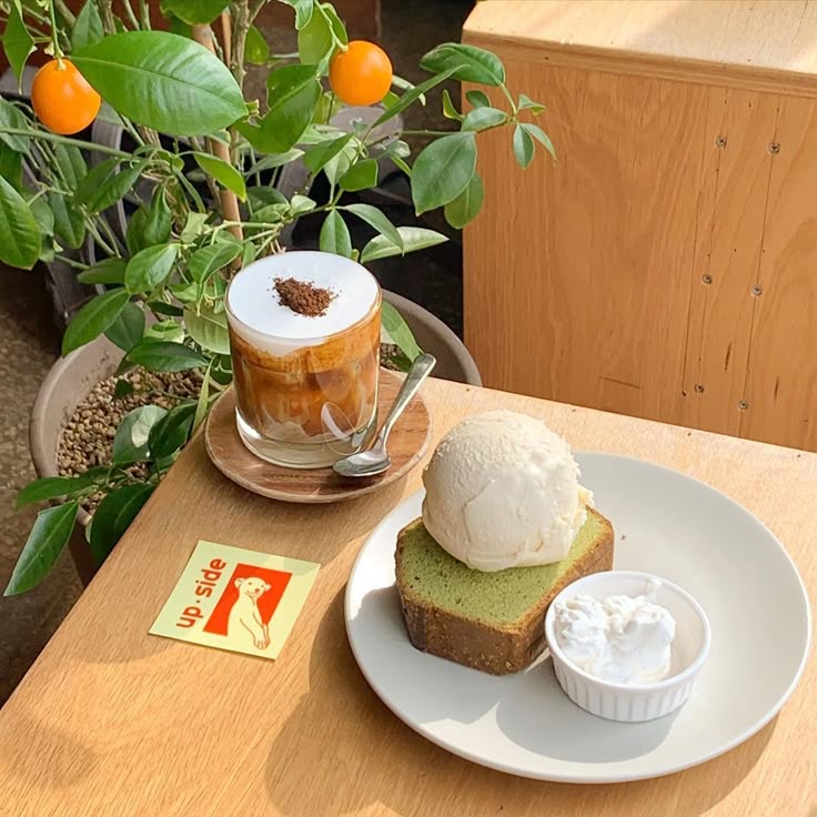 Iced coffee and matcha pound cake with ice cream on a cafe table beside a citrus plant