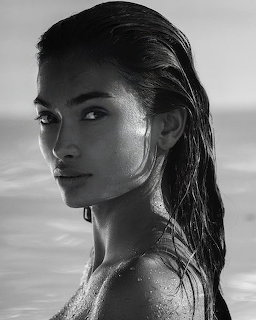 Black and white portrait of woman with wet hair looking over shoulder at beach