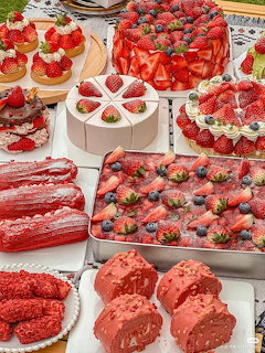 Assortment of strawberry cakes, tarts, and pastries displayed on a white table