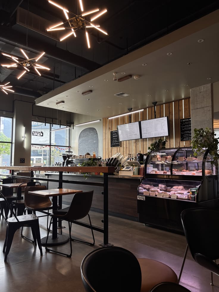 Modern cafe interior with tables, chairs, ceiling lights, and a pastry display counter