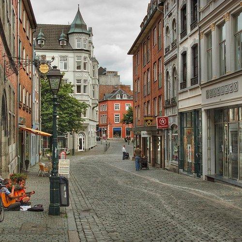 Cobblestone street between historic town buildings with a turreted white building in the distance