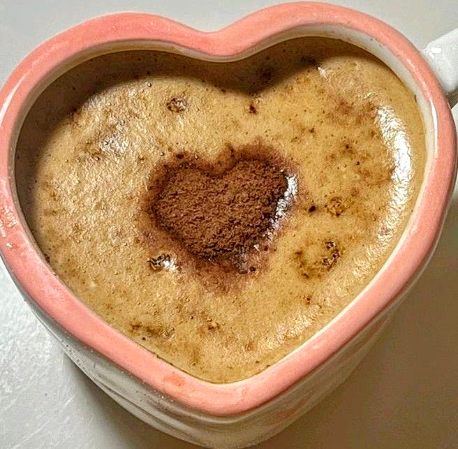 Golden turmeric latte with cinnamon heart design in pink heart-shaped mug