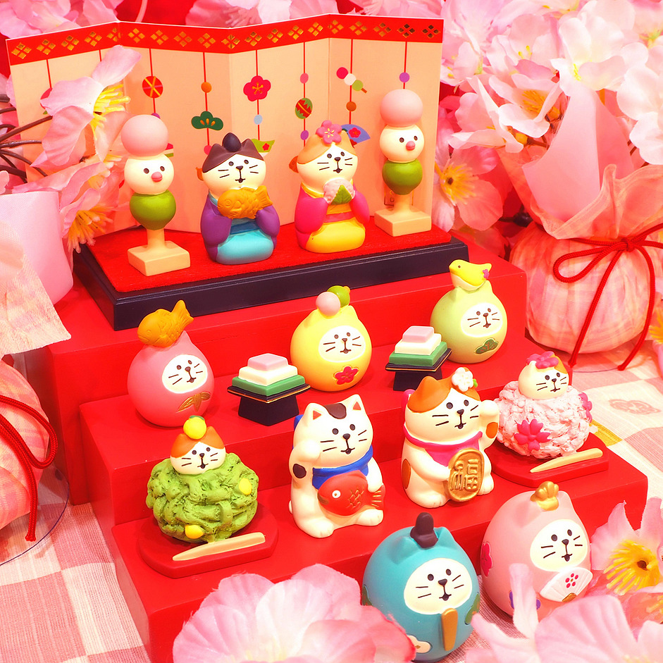 Colorful cat figurines on a red tiered display with pink flowers and decorations