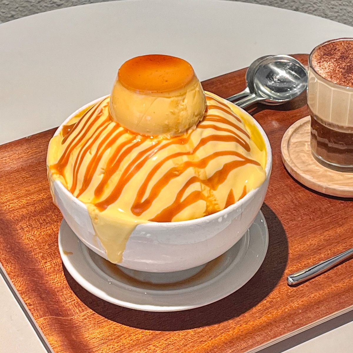 Caramel pudding dessert with whipped cream and caramel drizzle on wooden serving tray