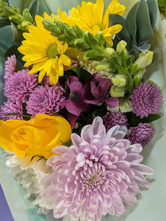 Colorful bouquet with yellow daisies, purple and pink flowers on light background