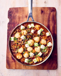 Blue skillet on wooden board with gnocchi, mushrooms, and herbs