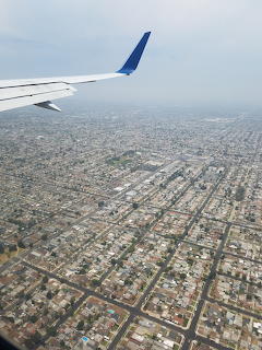 Aerial view of Los Angeles urban grid from airplane with wing visible against hazy sky