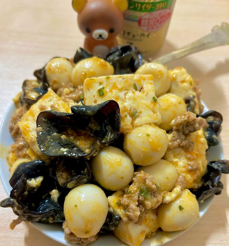 Bowl of mapo tofu with quail eggs and wood ear mushrooms in spicy ground meat sauce