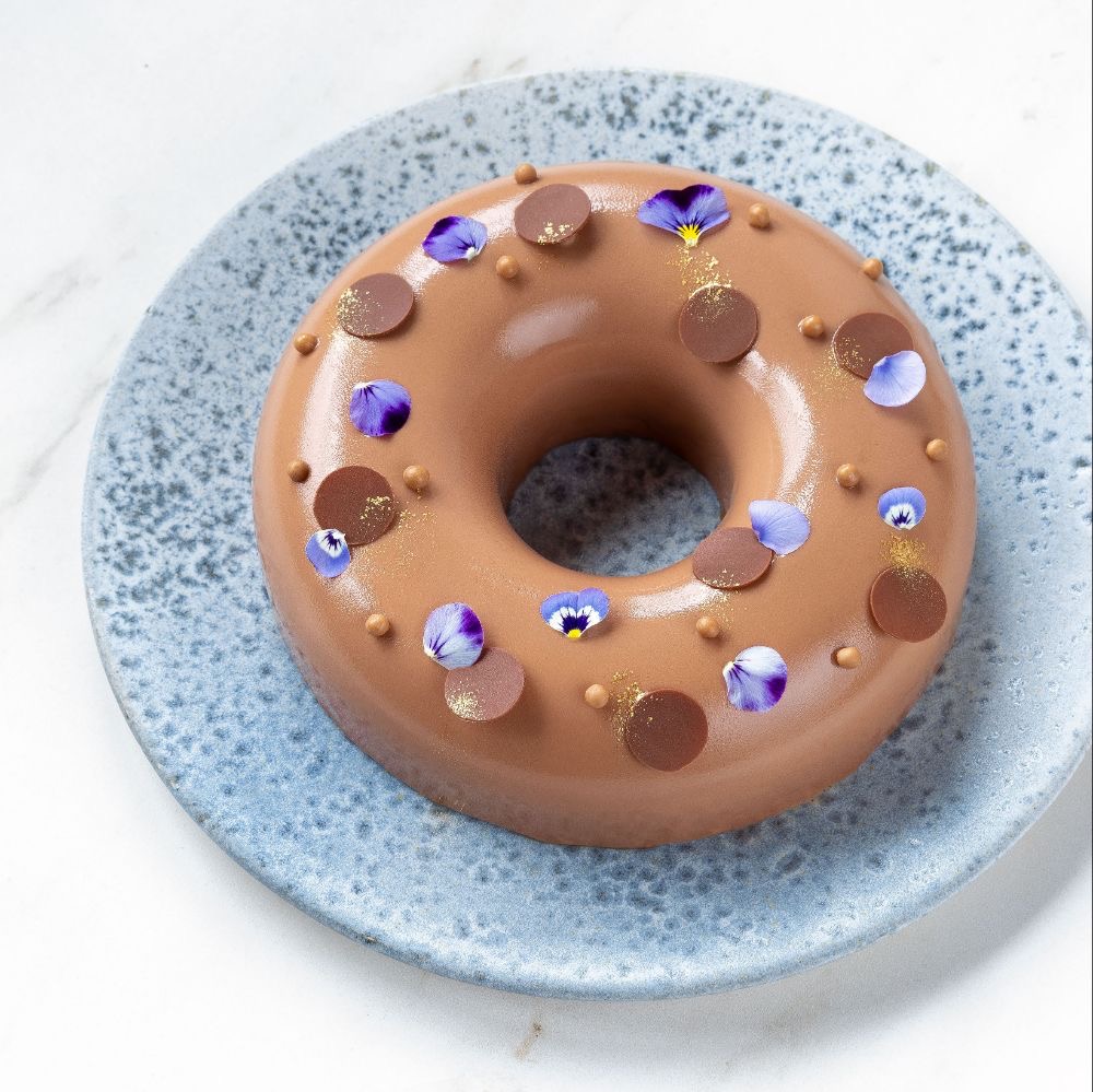 Chocolate donut with candy toppings on blue speckled plate