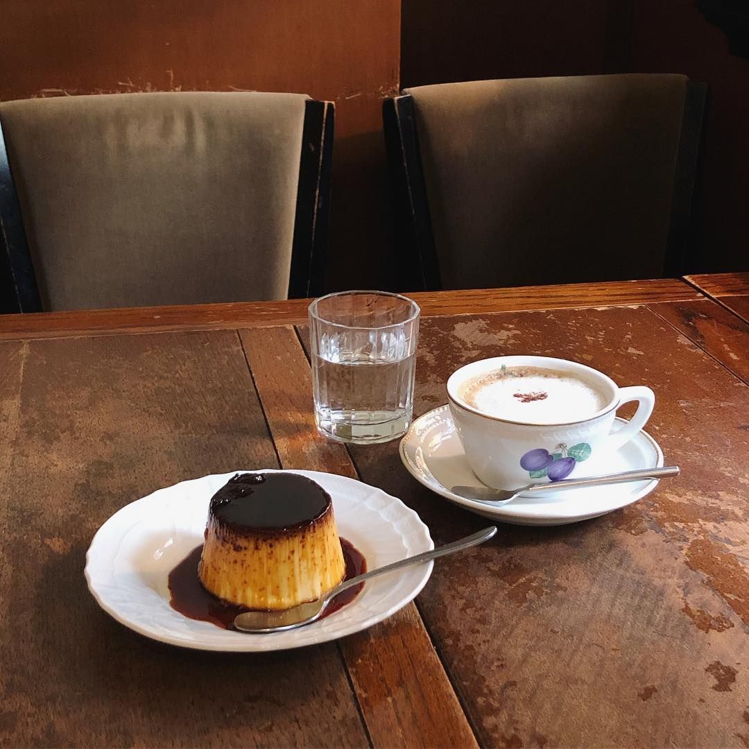 Coffee, water, and caramel pudding on a wooden cafe table