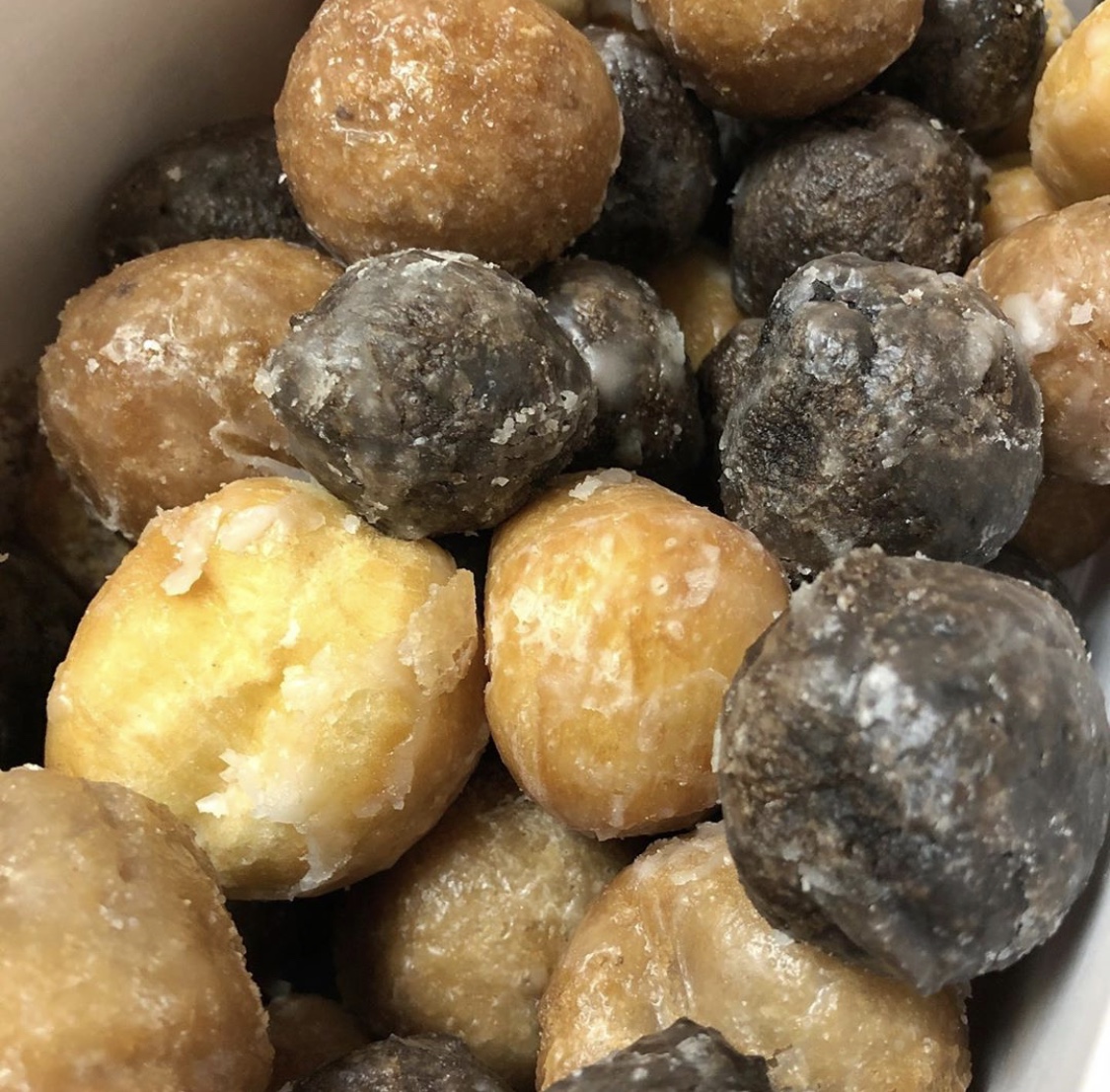 Bowl of mixed glazed donut holes in chocolate and vanilla flavors with sugar coating