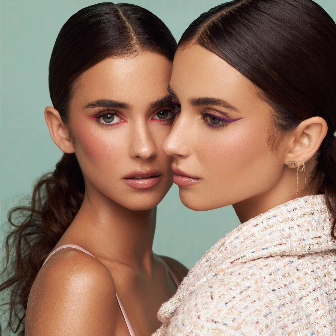 Close-up portrait of two women with sleek dark hair and soft makeup posing closely together