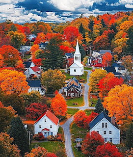 Aerial view of a Vermont village with white church and houses surrounded by colorful fall foliage