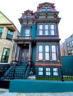 Colorful Victorian painted lady house with teal walls, ornate woodwork, and red and gold trim