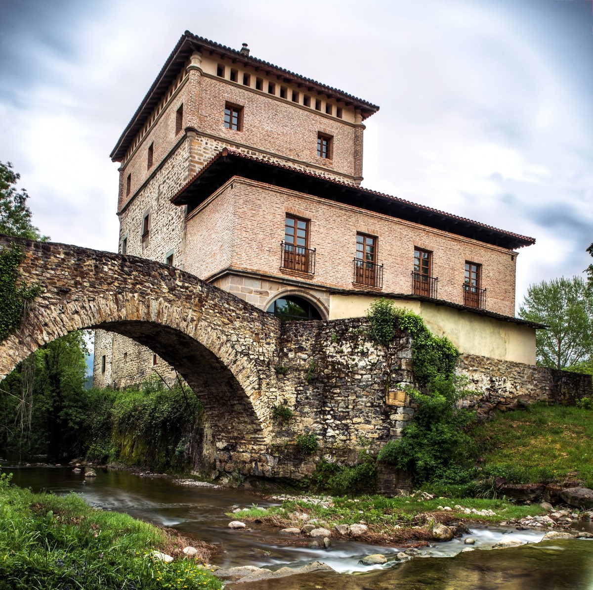 Medieval stone tower castle with bridge over stream in rural setting