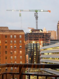 City buildings with a construction crane and illuminated building site at dusk
