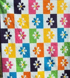 Patchwork quilt with white six-petal flowers on colorful squares in checkerboard layout