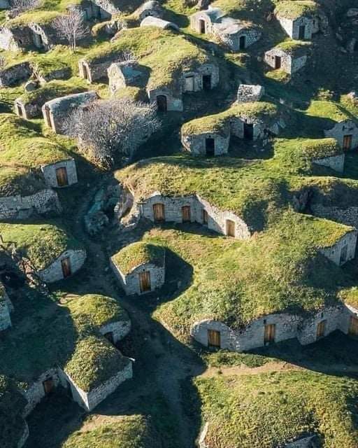 Aerial view of ancient grass-covered stone cellars with wooden doors on a hillside