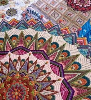 Close-up of a colorful geometric quilt with intricate patchwork and stitched mandala patterns.
