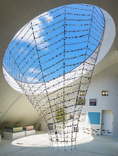 Large oval skylight with blue glass and geometric grid in modern white interior