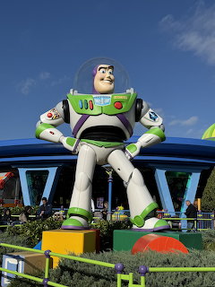Giant Buzz Lightyear figure at Disney theme park with colorful scenery and blue sky
