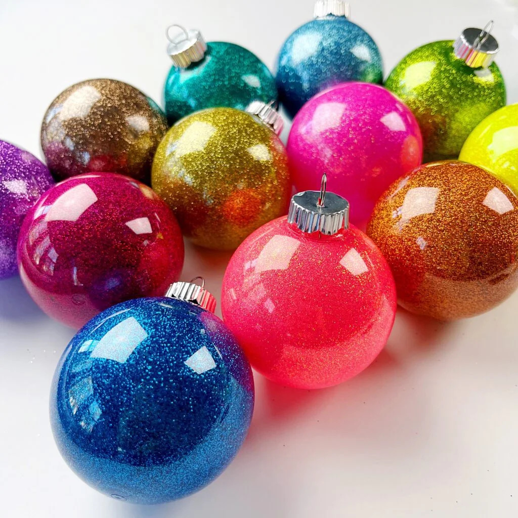 Collection of sparkly multicolored Christmas ornaments with glitter coating on white surface