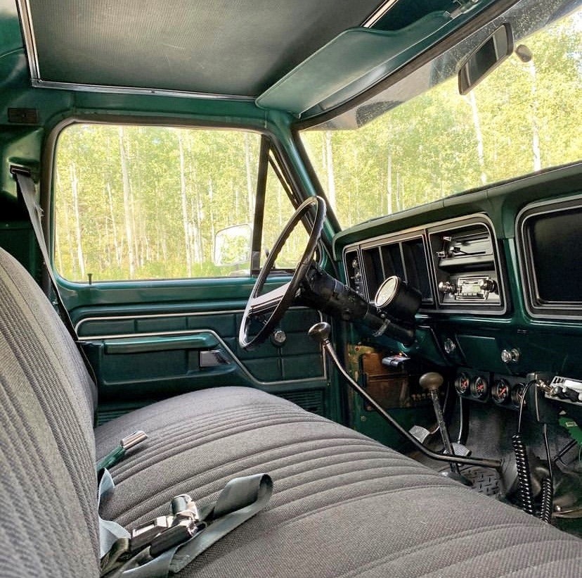Interior of a vintage pickup truck with bench seat, steering wheel, and dashboard