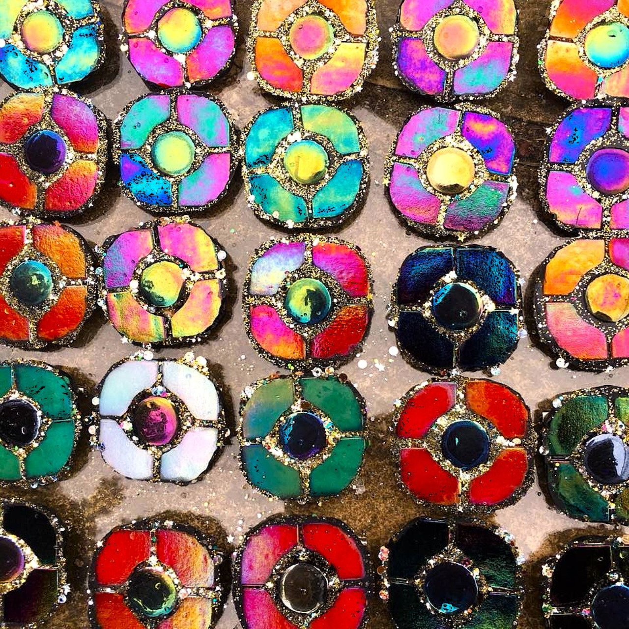 Grid of circular mosaic medallions with colorful iridescent tiles in floral patterns with metallic centers