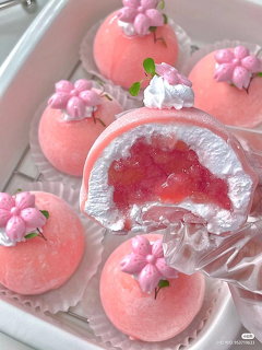 Pink dome cakes with flower decorations and red fruit filling on white tray
