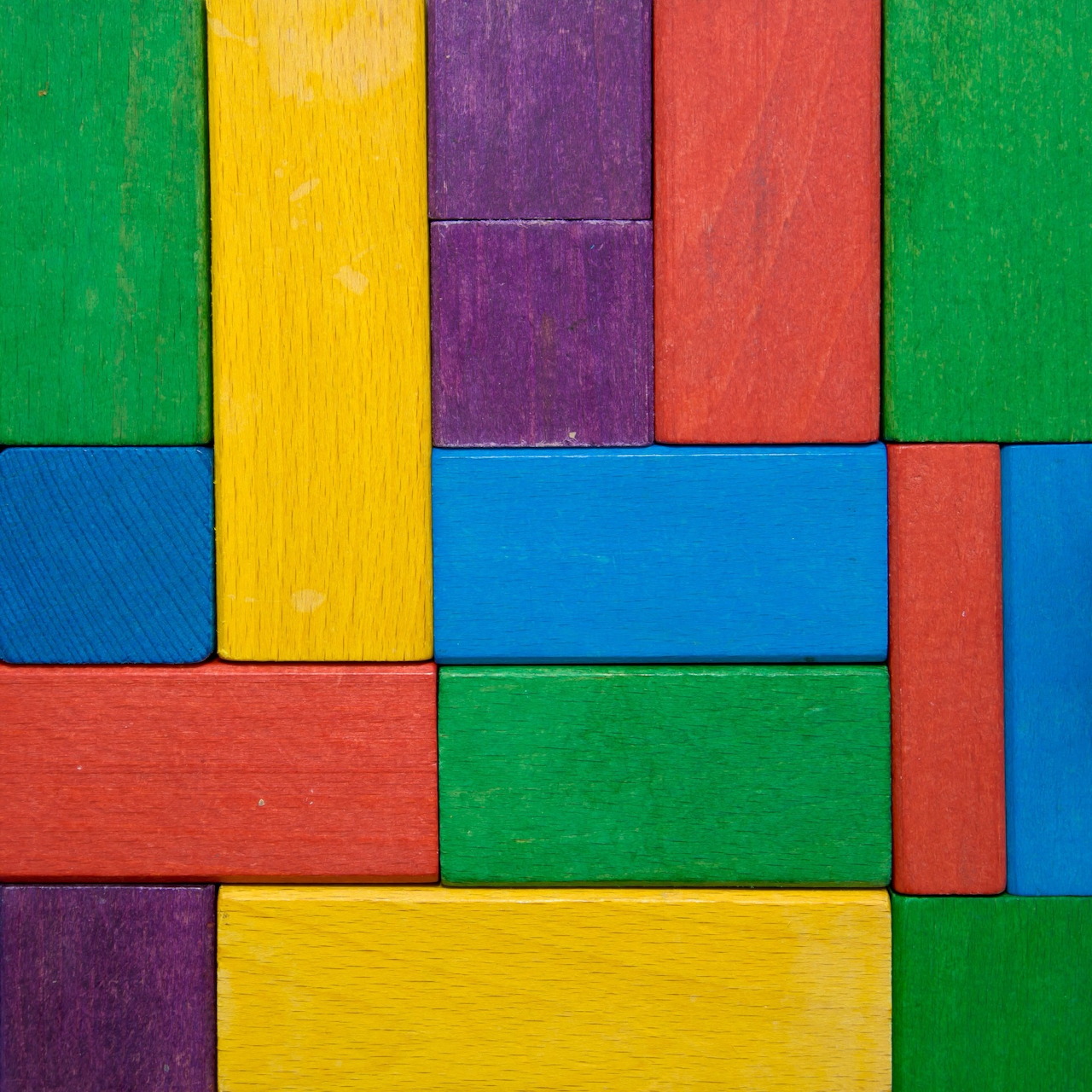 Colorful wooden blocks arranged in geometric pattern with green, yellow, purple, red and blue rectangles