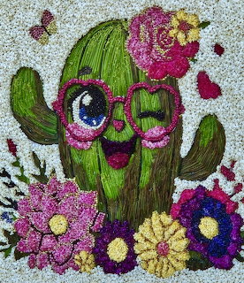 Colorful art of a smiling cactus with heart glasses surrounded by flowers and butterflies made from natural materials