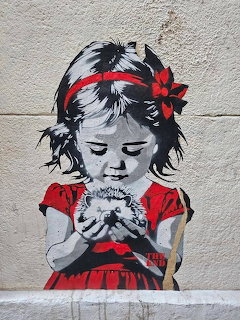 Street art of girl in red dress gently holding a bird